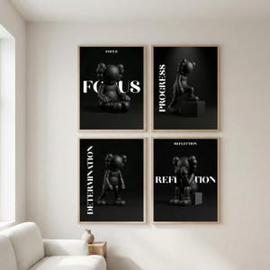 Puede incluir: Cuatro impresiones artísticas en blanco y negro enmarcadas. Cada impresión presenta una escultura negra de un personaje con X en los ojos, con palabras como "Focus", "Progress", "Determination" y "Reflection" en texto blanco.