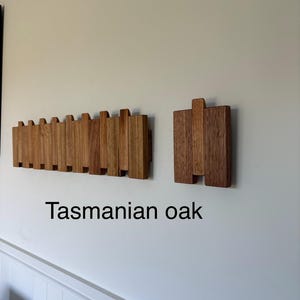 May include: A wall-mounted coat rack made of Tasmanian oak, featuring a long horizontal section with multiple vertical slats and a separate smaller square section with three vertical slats. The wood has a natural light brown grain finish.