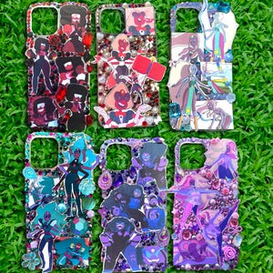 May include: Six decorative phone cases with cartoon character designs. Each case features a different character, with colorful gems and embellishments. The cases are on a green grassy background.