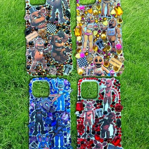 May include: Four phone cases decorated with character designs from the Five Nights at Freddy's video game series. Each case features a different color scheme, with rhinestones and other embellishments.
