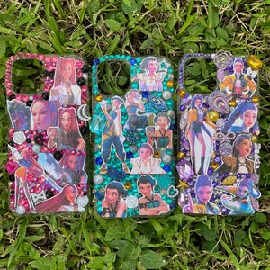 May include: Three decorative phone cases with colorful embellishments and images of people. The cases are decorated with rhinestones, pearls, and various images. The cases are set against a background of green grass.