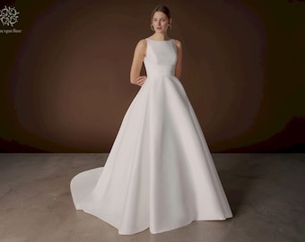 Abito da sposa a ball gown in raso: scollo a barca minimalista, schiena scoperta, strascico a cappella.