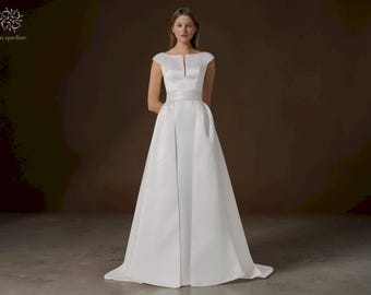 Elegante abito da sposa a trapezio: moderno scollo a barca, schiena scoperta con sopragonna.