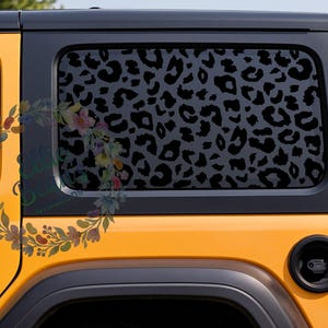 May include: A yellow vehicle side panel featuring a rear window covered in a black leopard print decal. The window graphic displays a repeating pattern of dark spots against a lighter gray background, applied to the glass of the orange-yellow car.