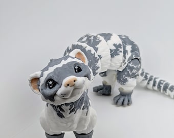 May include: A handcrafted, whimsical sculpture of a ferret. The ferret is primarily white with gray markings and a gray tail. The sculpture has a friendly expression and is posed on all fours. The background is a plain white.