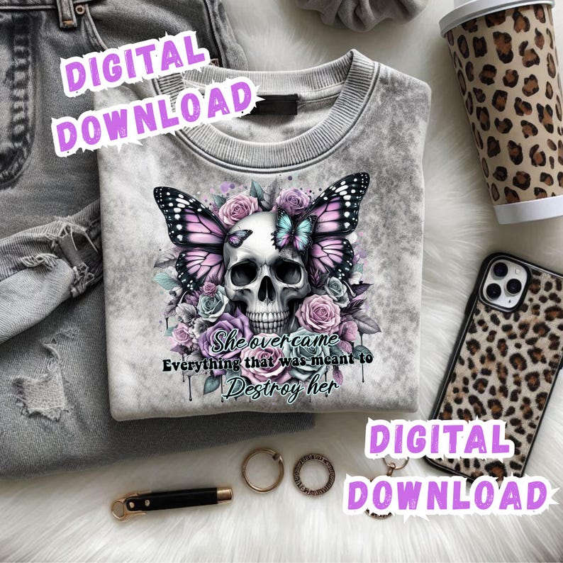 May include: A gray sweatshirt featuring a skull design with butterfly wings, surrounded by roses. The text "She overcame everything that was meant to destroy her" is below the skull. Accessories include a leopard print phone case and coffee cup.