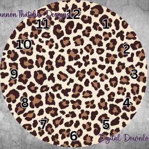 May include: A round clock face with a leopard print design in shades of brown and tan. Black numbers mark the hours. The text "Rhiannon Thatcher Designs" and "Digital Download" are visible.