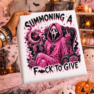 May include: A white square canvas print featuring a pink-hooded figure in a black chair, holding a mug labeled 'NOT TODAY SATAN'. The text reads 'SUMMONING A F*CK TO GIVE' with a crescent moon, roses, and a bat graphic in shades of pink and black.