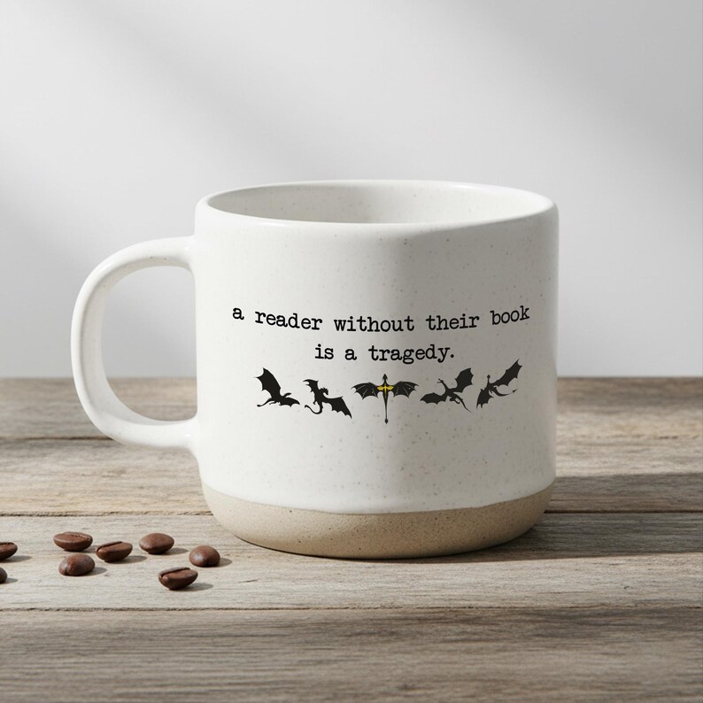 May include: A white ceramic mug with a black handle and the text "But First, Coffee" in a bold, black font. The mug is set against a neutral background, highlighting its simple design.