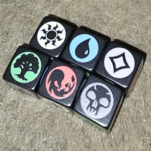 May include: Six black dice with white symbols representing the five elements of magic: fire, water, earth, air, and spirit, plus a skull symbol.