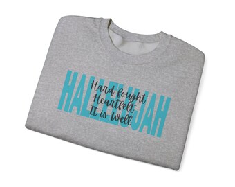 May include: Gray sweatshirt with the word "Hallelujah" in teal blue lettering. The words "Hard fought", "Heartfelt", and "It is well" are written in black lettering below the word "Hallelujah".