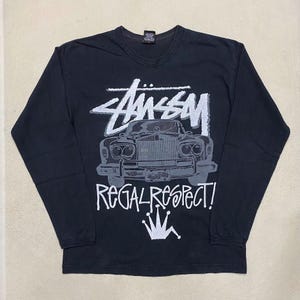 May include: Black long-sleeved t-shirt with a white graphic of a vintage car, the text "Stussy" and "Regal Respect!" and a crown.