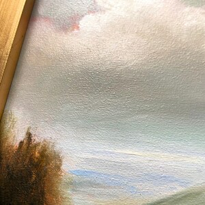 May include: A close-up of a painting depicting a landscape with a cloudy sky, a field of green grass, and a dark brown bush in the foreground.