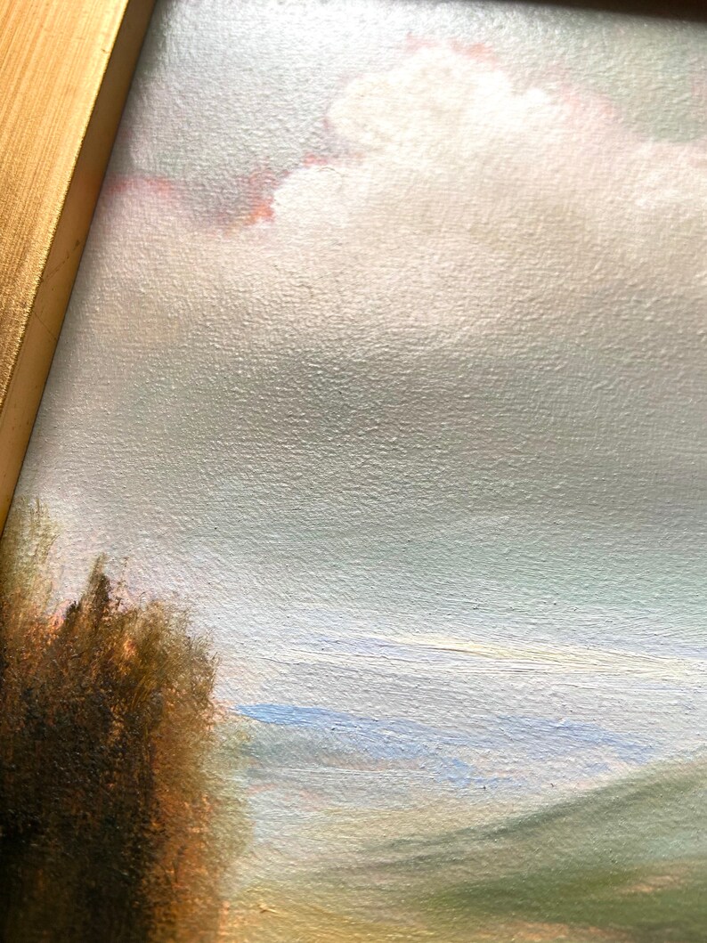 May include: A close-up of a painting depicting a landscape with a cloudy sky, a field of green grass, and a dark brown bush in the foreground.