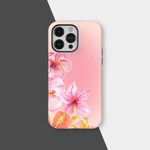 May include: A pink phone case featuring a watercolor design of hibiscus flowers in shades of pink, coral, and yellow. The case has a gradient background and a black camera module.