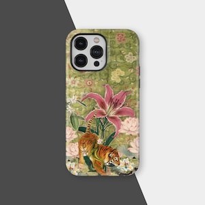 以下が含まれることがあります： ピンクのユリやその他の花の中にトラが描かれた、緑色の花柄の背景の携帯電話ケース。ケースは光沢仕上げで、カメラ用の切り抜きがあります。