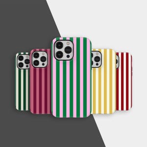 May include: A collection of colorful phone cases with vertical stripe patterns. The cases feature stripes in various color combinations, including green and pink, burgundy and pink, and yellow and white. The cases are arranged in a row.