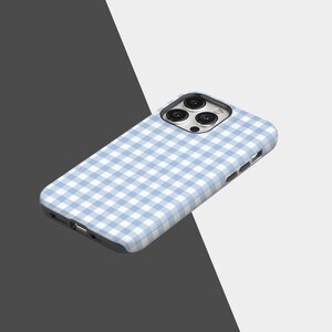 May include: A light blue and white gingham patterned phone case. The case is designed to fit a smartphone, with cutouts for the camera and charging port. The case is made of a hard, protective material.