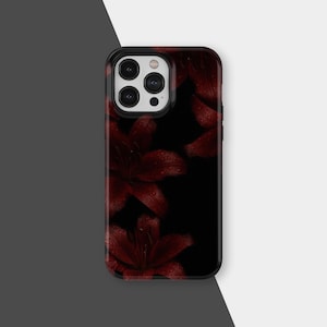 Könnte beinhalten: Schwarze Handyhülle mit einem dunkelroten Blumendesign und Wassertropfen. Die Hülle hat eine glänzende Oberfläche und einen schwarzen Rand. Die Blumen sind Lilien, und die Gesamtästhetik ist elegant und von der Natur inspiriert.