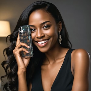 May include: A smartphone case featuring a detailed illustration of a bookshelf with books and a mystical forest scene. The case is held by a person with long, dark hair and a black dress. The background is a soft gray.