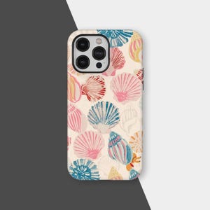 Puede incluir: Una funda de teléfono con un patrón repetido de conchas marinas coloridas en tonos rosa, azul, rojo y amarillo sobre un fondo crema. La funda tiene un módulo de cámara negro.