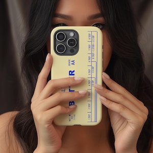 May include: A light yellow phone case with a blue butter measurement chart. The case features the word "BUTTER" in blue, along with measurements for tablespoons and cups. The phone case is held in front of a person.