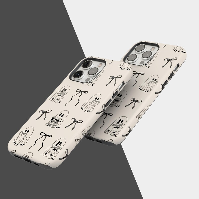 May include: Two phone cases with a cream-colored background and a repeating pattern of black ghost illustrations and bows. The cases have a glossy finish and a camera cutout.