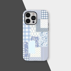 May include: A phone case featuring a patchwork design in various shades of blue and white. The case incorporates patterns like gingham, floral, and striped elements, creating a cohesive and visually appealing aesthetic. The case has a black camera module.