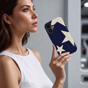May include: A navy blue phone case featuring a cream-colored star design. The case has a smooth finish and is designed to fit a smartphone. The stars are of varying sizes and are arranged on the back of the case.