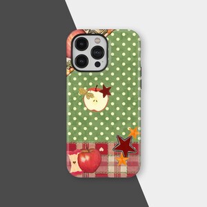 May include: A phone case with a green polka dot pattern and apple and star designs. The case has a patchwork design with red and white plaid accents and a red apple illustration.