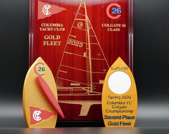May include: A dark wood plaque featuring a laser-etched sailboat and text reading Columbia Yacht Club Gold Fleet 2023. Two gold-colored awards stand in front, one with a red pennant and C26 logo, the other with SailSet3D and Second Place text.