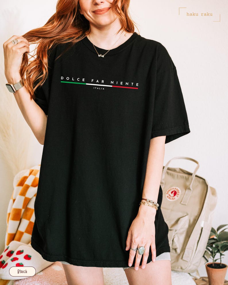 May include: Black t-shirt with the words "DOLCE FAR NIENTE" in white, with a green, white, and red stripe design. The word "ITALIA" is below the main text. The shirt is a casual, oversized style.