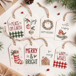 Op de afbeelding: Acht rechthoekige witte papieren cadeaulabels met lussen van jutekoord. De ontwerpen bevatten teksten zoals Peace on Earth, Joy, Happy Holidays, Winter Wishes, Merry & Bright, Be Merry en Warm Wishes, met illustraties van kerstballen, een krans, een roodborstje, een kerstsok en een peperkoekhuisje.