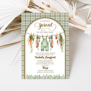 Puede incluir: Invitación a un baby shower con un fondo a cuadros verdes y un arco decorativo. El arco presenta un tendedero con zanahorias, vegetación y un peto. El texto dice "A Little Sprout Is On The Way" y los detalles del baby shower de Isabella Langford.