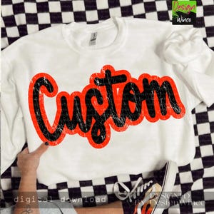 May include: White crewneck sweatshirt with the word "Custom" in a distressed black font with a red outline. The sweatshirt is displayed on a black and white checkered surface.