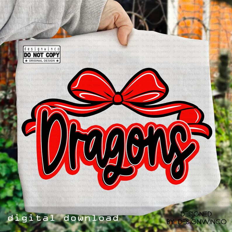Op de afbeelding: Een witte draagtas met het woord "Dragons" in zwarte letters met een rode omlijning en een rode strik. De woorden "digitale download" en "ontworpen door designwinco" zijn ook zichtbaar. Het ontwerp staat op een witte achtergrond.