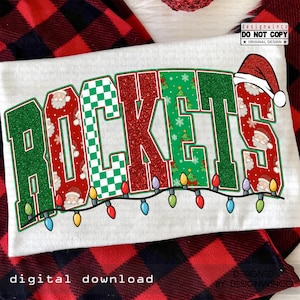 Könnte beinhalten: Weißes T-Shirt mit dem Wort "ROCKETS" in einem festlichen Design. Die Buchstaben sind grün, rot und weiß, mit Weihnachtsmann, Weihnachtsbäumen und Schachbrettmustern. Eine Lichterkette mit bunten Lichtern verläuft unter dem Wort. Der Text "DIGITAL DOWNLOAD" steht unten.