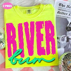 May include: A neon yellow t-shirt with the words "RIVER bum" in bright pink and teal script. The shirt is folded and has a tag at the neckline. A newspaper and disco ball are in the background.