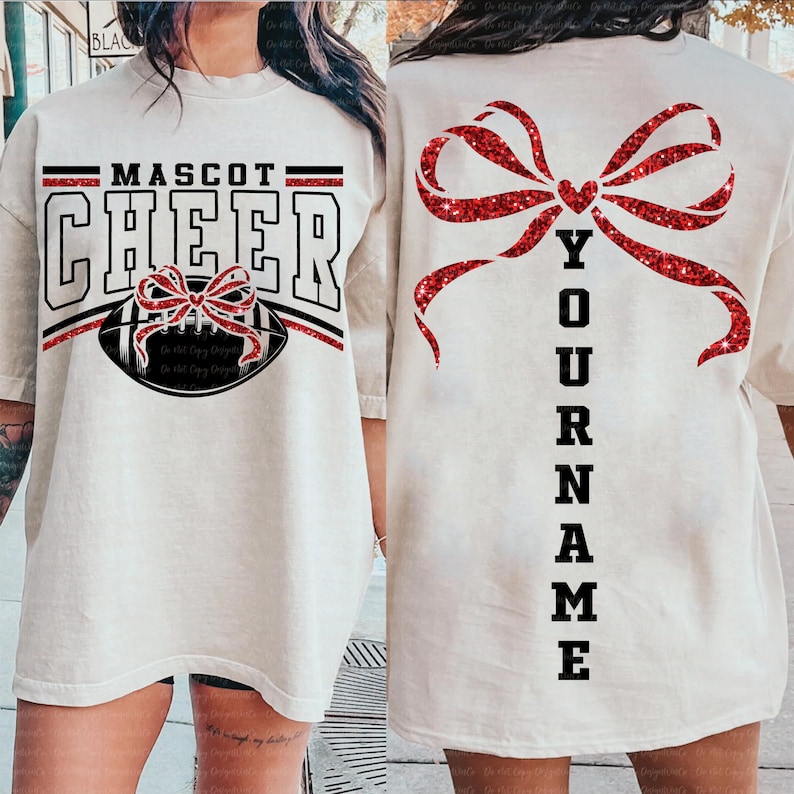 May include: Cream-colored t-shirt with the words "MASCOT CHEER" in black and red, featuring a football and bow design. The back of the shirt has a large red glitter bow and the word "YOUR NAME" in black.