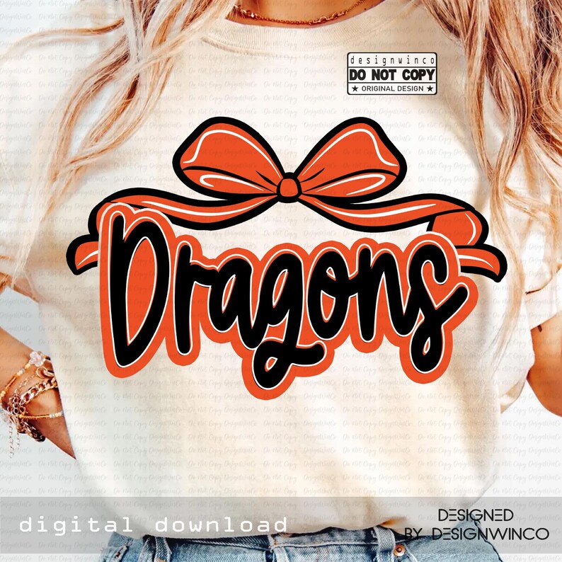 Op de afbeelding: Een cr&egrave;mekleurig T-shirt met het woord "Dragons" in een vet, zwart lettertype met een oranje omlijning. Boven het woord staat een oranje strik. Het shirt bevat ook de tekst "digitale download" en "ontworpen door designwinco".