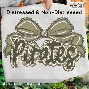 May include: A digital design featuring the word "Pirates" in a camouflage pattern, overlaid with a decorative bow. The design includes the text "Distressed & Non-Distressed" and "Digital Download". The design is by DesignWinco.