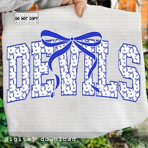 Puede incluir: Una camiseta blanca con la palabra "DEVILS" en letras grandes, azules y estampadas. Un lazo azul está centrado encima de la palabra. Las letras están rellenas con un patrón de lazos y corazones. También se ve el texto "digital download" y "DESIGNED BY DESIGNWINCO".