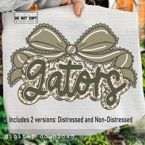 May include: A digital download design featuring the word "Gators" in a camouflage pattern, with a decorative bow above. The design includes the text "Includes 2 versions: Distressed and Non-Distressed" and "digital download". The design is by Designwinco.