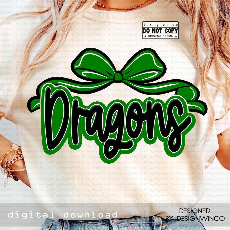 Op de afbeelding: Een cr&egrave;mekleurig T-shirt met een groene strik en het woord "Dragons" in een vetgedrukte, zwarte letter met een groene omlijning. Het ontwerp bevat de tekst "digitale download" en "ontworpen door designwinco".