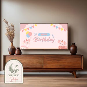 May include: A pink and blue birthday banner with the text "Happy Birthday" and two cartoon axolotls on a TV screen. The TV is on a wooden entertainment center with a vase of dried flowers on the left and a vase on the right.