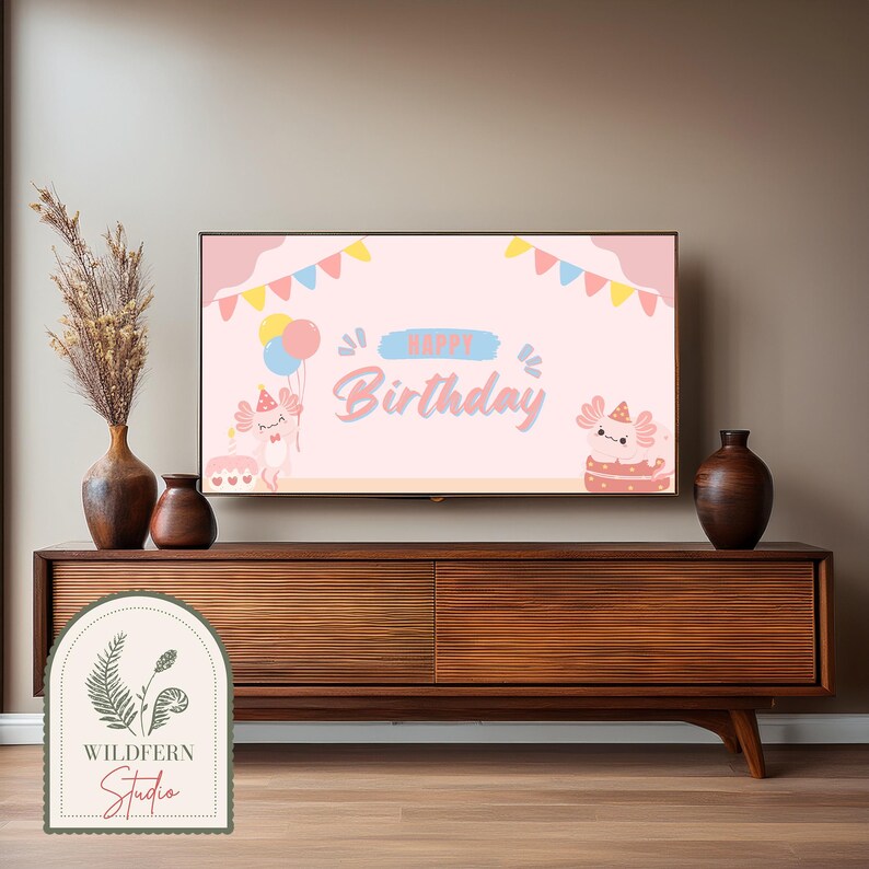 May include: A pink and blue birthday banner with the text "Happy Birthday" and two cartoon axolotls on a TV screen. The TV is on a wooden entertainment center with a vase of dried flowers on the left and a vase on the right.