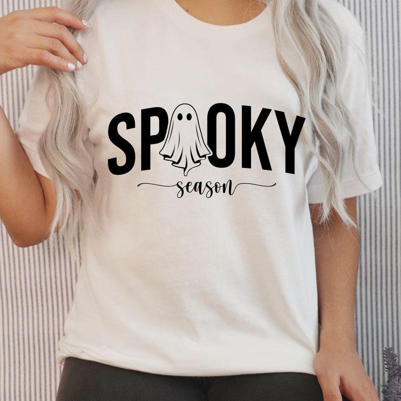 K&ouml;nnte beinhalten: Wei&szlig;es T-Shirt mit dem schwarzen Schriftzug "SPOOKY season" und einer Geistergrafik. Das Shirt hat einen Rundhalsausschnitt und kurze &Auml;rmel. Das Design ist mittig auf der Vorderseite platziert.