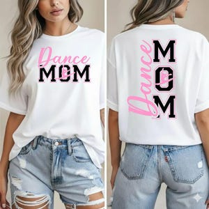May include: White t-shirt with the text "Dance MOM" in pink and black block letters on the front and back. The back of the shirt has the words "Dance" and "MOM" vertically, with a dancer silhouette in the "O".