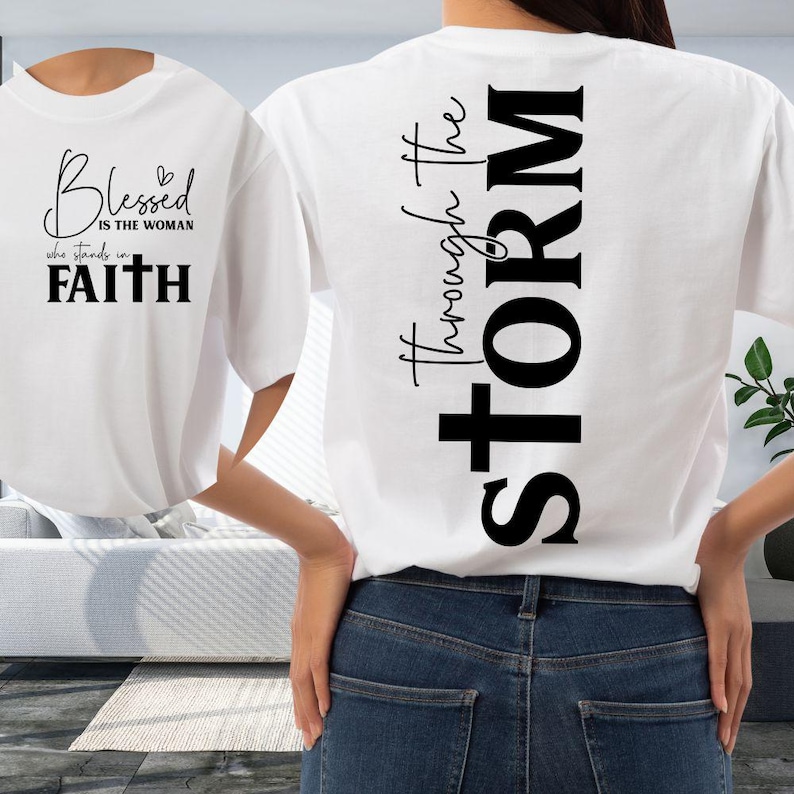 May include: White t-shirt with black text. The front of the shirt says "Blessed is the woman who stands in Faith." The back of the shirt says "Through the STORM."