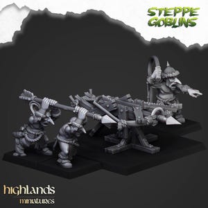 Puede incluir: Una escena en miniatura con tres figuras de duendes operando una balista de madera. Las figuras son grises, con orejas puntiagudas y visten ropa con adornos de piel. La balista está detallada con cuerdas y flechas. El texto "Steppe Goblins" y "highlands miniatures" son visibles.
